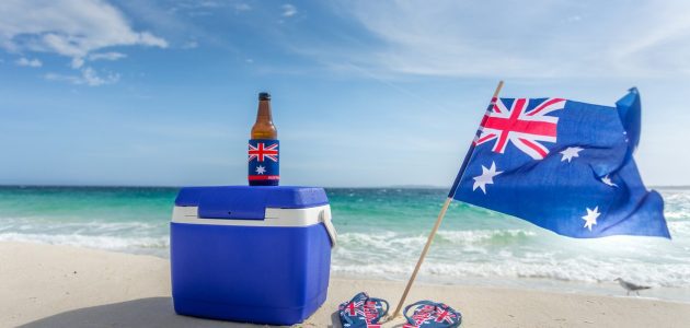 Quinessentially Australian summer.  Esky, beer bottle in a cooler, thongs and Australian flag on a beautiful beach on summer day